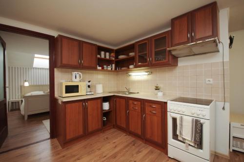 una pequeña cocina con armarios de madera y microondas en Gyulai idill apartman, en Gyula