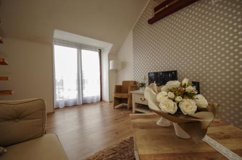 a living room with a vase with flowers in it at Gyulai idill apartman in Gyula