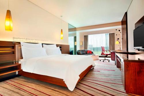a hotel room with a large bed and a television at Le Meridien Coimbatore in Coimbatore