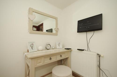 a bathroom with a tv on a wall with a toilet at Gyulai idill apartman in Gyula