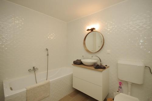 a bathroom with a sink and a tub and a mirror at Gyulai idill apartman in Gyula