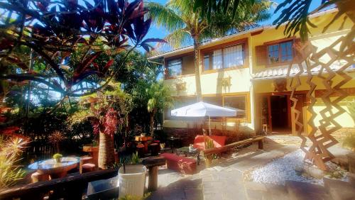 a building with a patio with tables and chairs at 3 Palmeiras Guest Lounge in Miguel Pereira