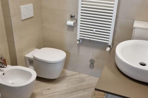 een badkamer met een wit toilet en een wastafel bij Appartamento incantevole con uso piscina e spa in Magliolo