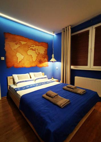 Un dormitorio azul con una cama grande con toallas. en Apartament Morski z ogródkiem, en Rumia