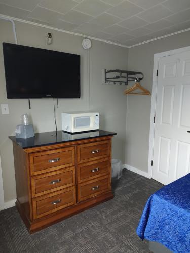 a bedroom with a dresser with a tv on the wall at Vacationland Inn & Suites in Brewer