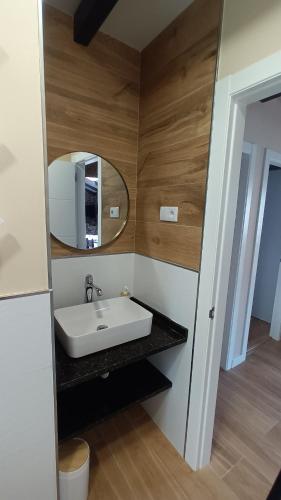 ein Bad mit einem Waschbecken und einem Spiegel in der Unterkunft A caseta de Mourelle in Amés