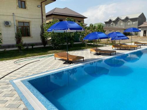 a swimming pool with blue umbrellas and lounge chairs and a pool at GREEN APPLE HOTEL in Tashkent