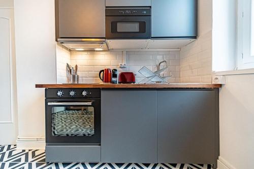 eine Küche mit einem Backofen und einer Mikrowelle in der Unterkunft Le Bon Pasteur-cosy 2 pers- Croix Rousse in Lyon