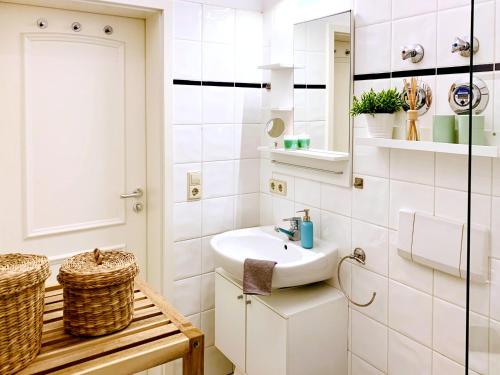een witte badkamer met een wastafel en een spiegel bij Zentrumsnahe Ferienwohnung mit ruhigem Balkon - "Arthur" in Leipzig