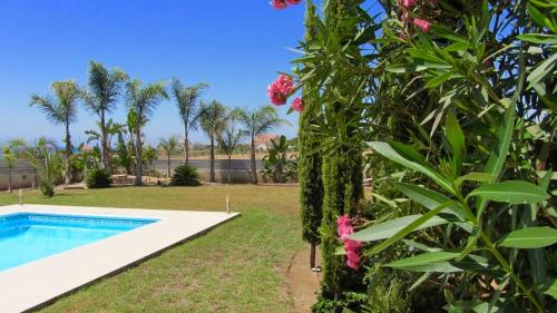 un giardino con piscina e un cespuglio con fiori rosa di Villa Aris ad Ayios Theodhoros