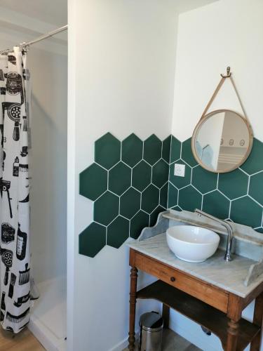 une salle de bain avec un lavabo et un miroir dans l'établissement Les Magnolias, à Tourville-la-Chapelle