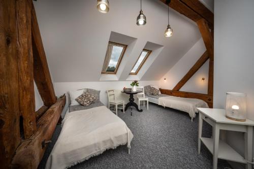 a attic room with two beds and a table at Miły Młyn in Lubrza