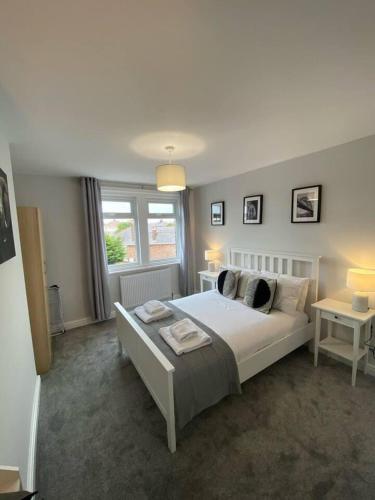 a bedroom with a bed and two tables and a window at Storey Apartment - 2 Bedroom upstairs flat in Newbiggin-by-the-Sea