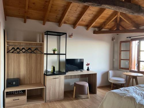 een slaapkamer met een bed en een bureau met een televisie bij Melofegaro Guesthouse in Palaios Panteleimon