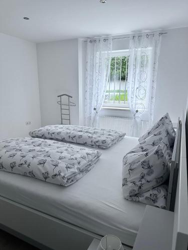 a white bedroom with two beds and a window at Ferienwohnung Jasmin in Traben-Trarbach