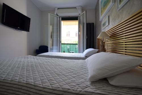 a bedroom with two beds and a television and a window at mentamarina in Porto Recanati