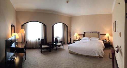 a bedroom with a large bed and two windows at Yindo Jasper Hotel Zhuhai in Zhuhai