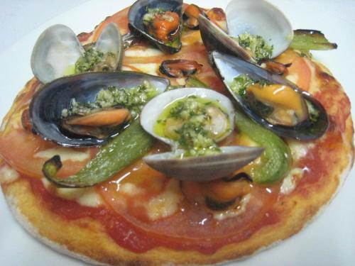 a pizza with oysters and vegetables on a plate at Hostal Stella Del Mare in Camariñas
