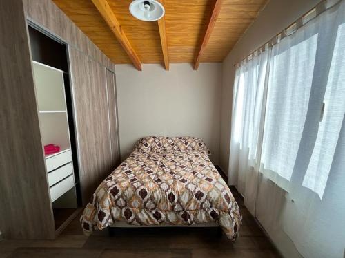 a small bedroom with a bed and a window at Cabañas PH in Trevelín