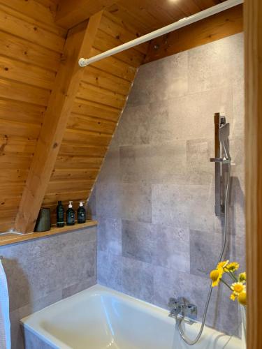 a tub in a bathroom with a wooden ceiling at Kleines Chalet im Erzgebirge mit Sauna und Kamin in Rechenberg-Bienenmühle