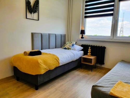 een slaapkamer met een bed met een gele deken bij HappyStay Gold in Gliwice