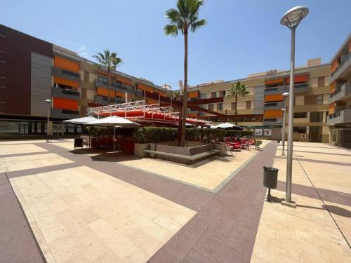un patio con mesas y sombrillas en un edificio en Alcalá Center Playa en Alcalá