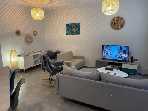 uma sala de estar com um sofá, uma mesa e uma televisão em Petite maison Montbard 1 chambre em Montbard