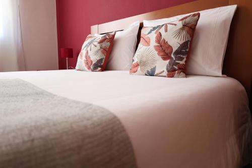 een slaapkamer met een bed met witte lakens en kussens bij Apartamento - Férias Felizes Portimão in Portimão