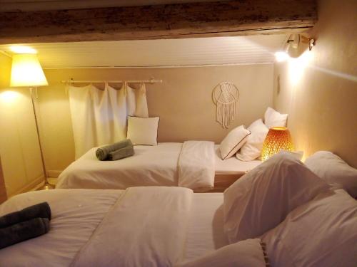 a hotel room with two beds with white sheets at La maison perchee in Aigues-Mortes