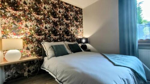 a bedroom with a bed and a floral wall at Apartament Pod Czereśnią in Suwałki