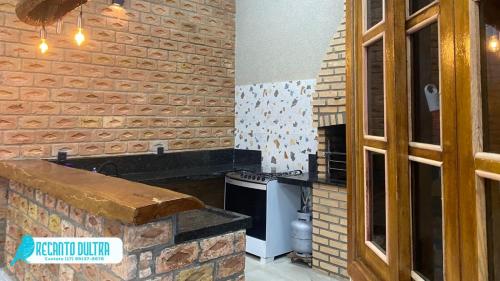 a kitchen with a stove and a brick wall at Recanto Dutra in Olímpia