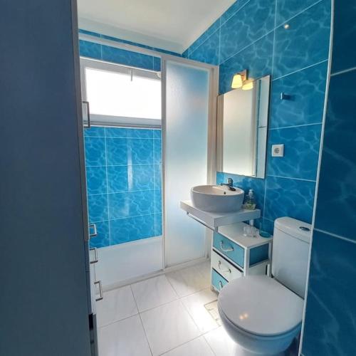 a blue tiled bathroom with a toilet and a sink at Casa do Portão Azul - Dourada in Atouguia da Baleia