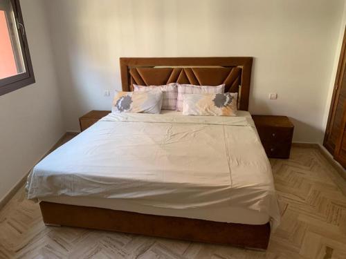 um quarto com uma cama grande com lençóis brancos e almofadas em Appartement calme, Guéliz em Marrakech