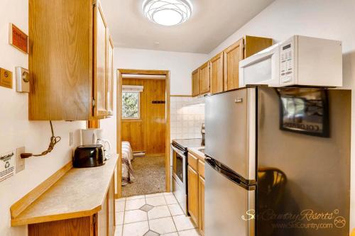 uma cozinha com um frigorífico de aço inoxidável e armários de madeira em Economical, Cozy Condo Near Main St Access to Spacious Lobby, Hot Tubs PM5B em Breckenridge