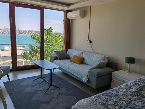 a living room with a couch and a large window at Bosphorus Menekshe Rezidances in Istanbul