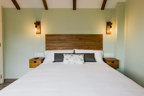 a bedroom with a large white bed with a wooden headboard at O Lar de Pereiras in Meaño