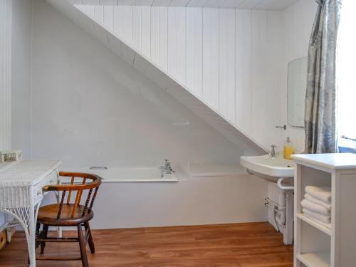 uma casa de banho branca com um lavatório e uma cadeira. em Mossdale em Rockcliffe