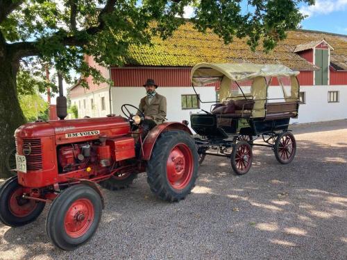 a man sitting on a tractor and a carriage at Fin lägenhet mitt på Bjärehalvön in Båstad