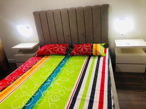 a bed with colorful sheets and pillows on it at Sea & Mountain Lukove Apartment in Lukovë