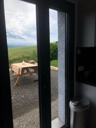 - une vue sur une table depuis une porte coulissante en verre dans l'établissement Location appartement T2 - 1 chambre le bourget du lac, au Bourget-du-Lac