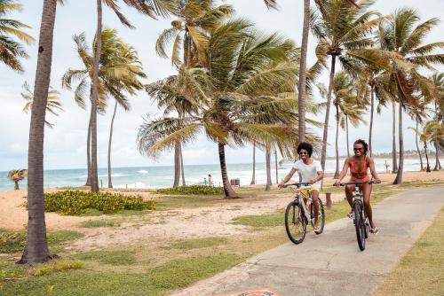 due persone in bicicletta su un sentiero vicino alla spiaggia di Sauipe Resorts Ala Mar - All Inclusive a Costa do Sauipe