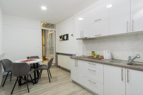 uma cozinha com armários brancos e uma mesa e cadeiras em Stan lux Kašmir em Bugojno