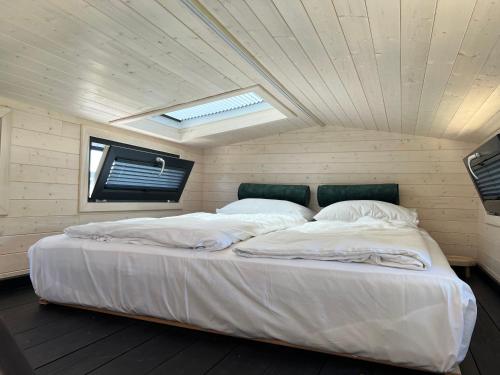 a large white bed in a room with a ceiling at Tiny House Lovely Sunshine in Giethoorn