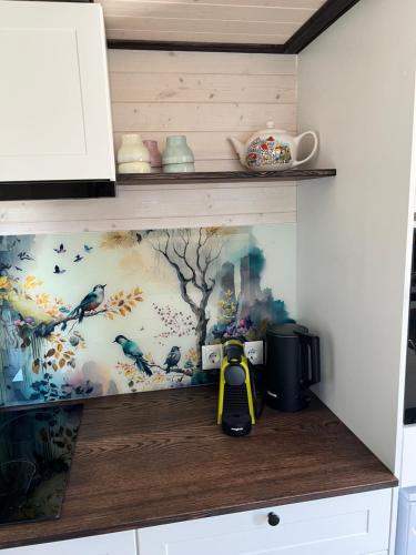 a kitchen shelf with a painting on the wall at Tiny House Lovely Sunshine in Giethoorn