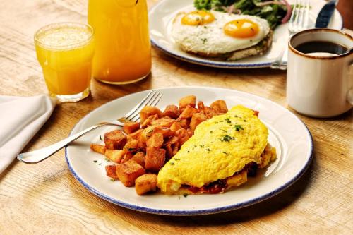 two plates of breakfast food with eggs and potatoes on a table at Staybridge Suites Chicago O'Hare - Rosemont by IHG in Rosemont