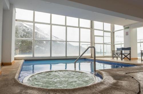 bañera de hidromasaje en una habitación con ventana grande en Departamento Hosteria del Cerro en San Carlos de Bariloche