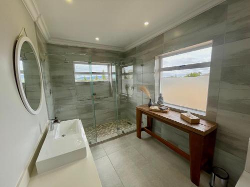 a bathroom with a shower and a sink and a mirror at The Little Palm in Bloubergstrand