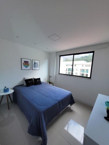 een slaapkamer met een blauw bed en een raam bij Cobertura Piemonte in Itaipava