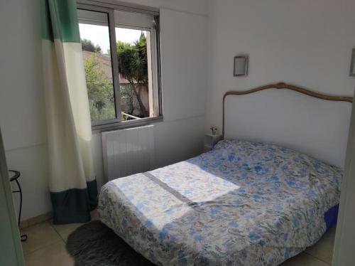 Schlafzimmer mit einem Bett und einem Fenster in der Unterkunft Joli appartement avec cour privé à 150m de la mer in Sanary-sur-Mer