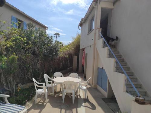 eine Terrasse mit einem Tisch und Stühlen sowie eine Katze auf einer Treppe in der Unterkunft Joli appartement avec cour privé à 150m de la mer in Sanary-sur-Mer